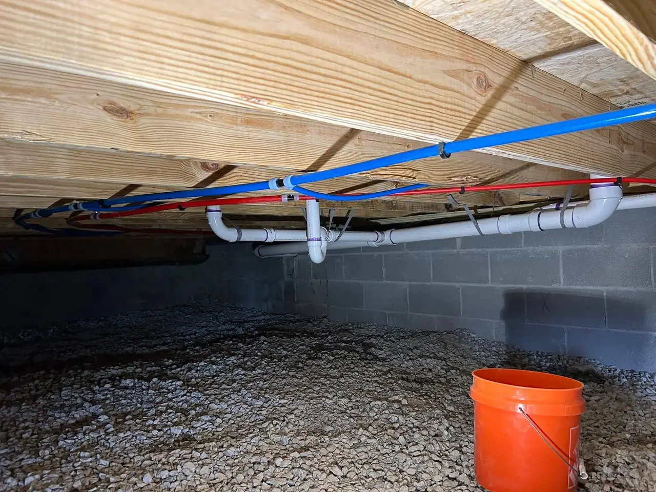 New PEX hot and cold supply lines and white PVC drain piping installed under a Murfreesboro home